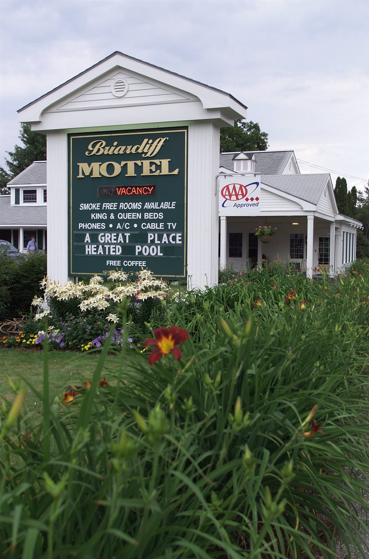 Briarcliff Motel roadside sign with AAA Approved badge framed by orange daylilies