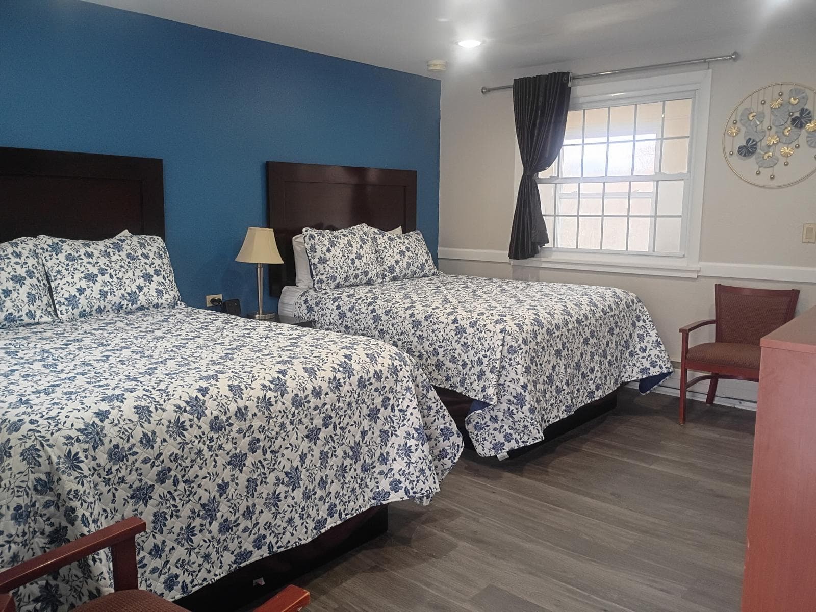 Two queen beds with blue floral bedding and blue accent wall at Briarcliff Motel